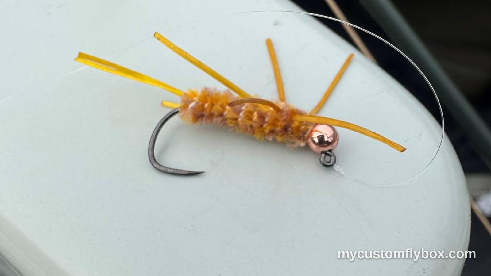Tan rubber-leg terrestrial fly with a copper bead resting on a white boat seat