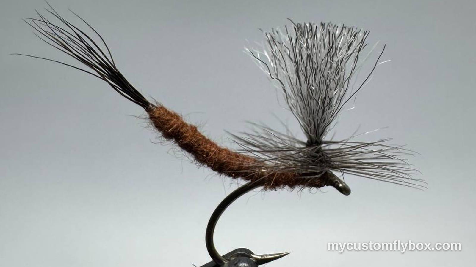 Brown parachute mayfly dry fly with gray hackle and a white post held in a fly-tying vise