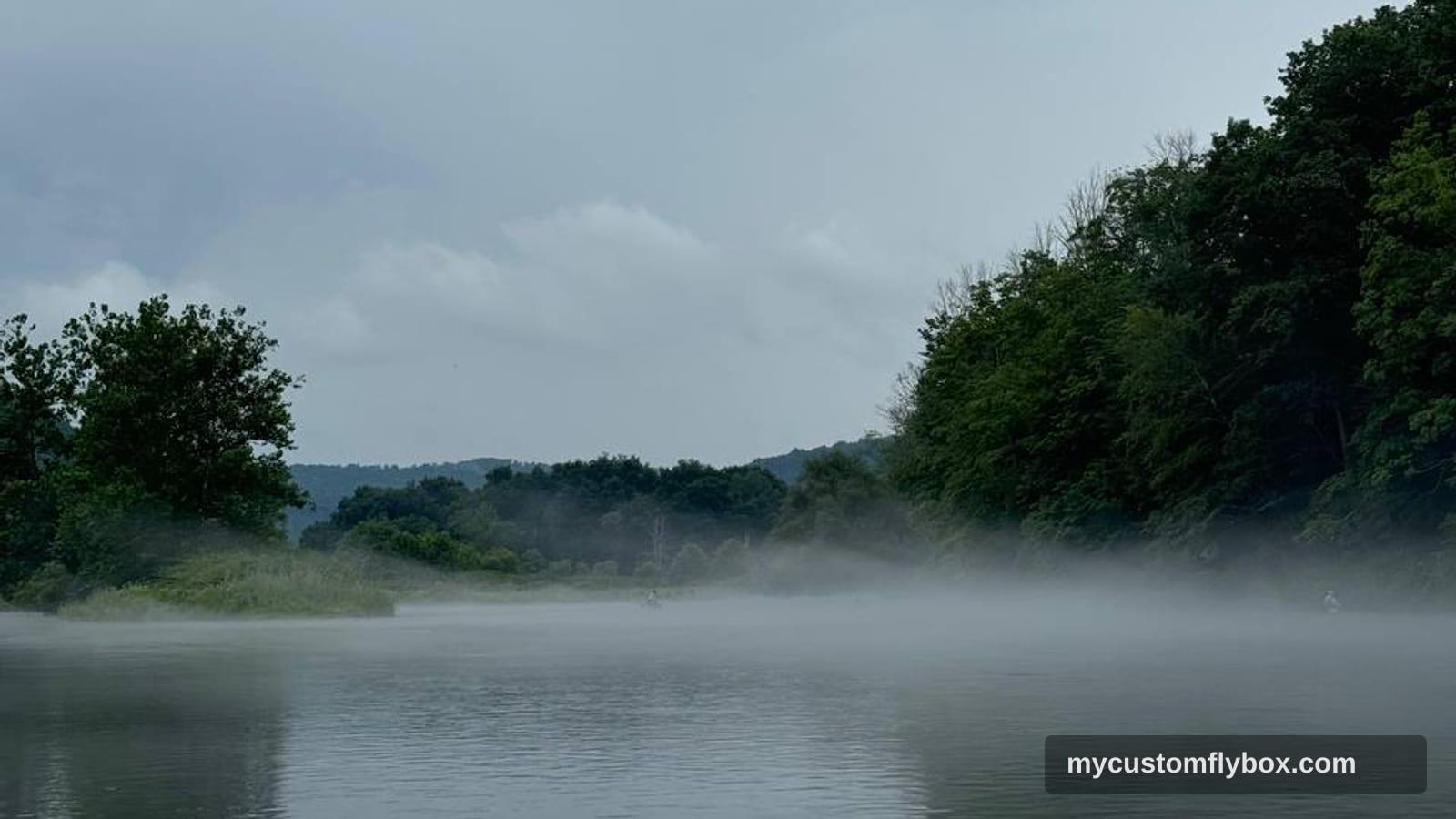 Morning fog lifting off Penns Creek with wooded banks and calm trout water