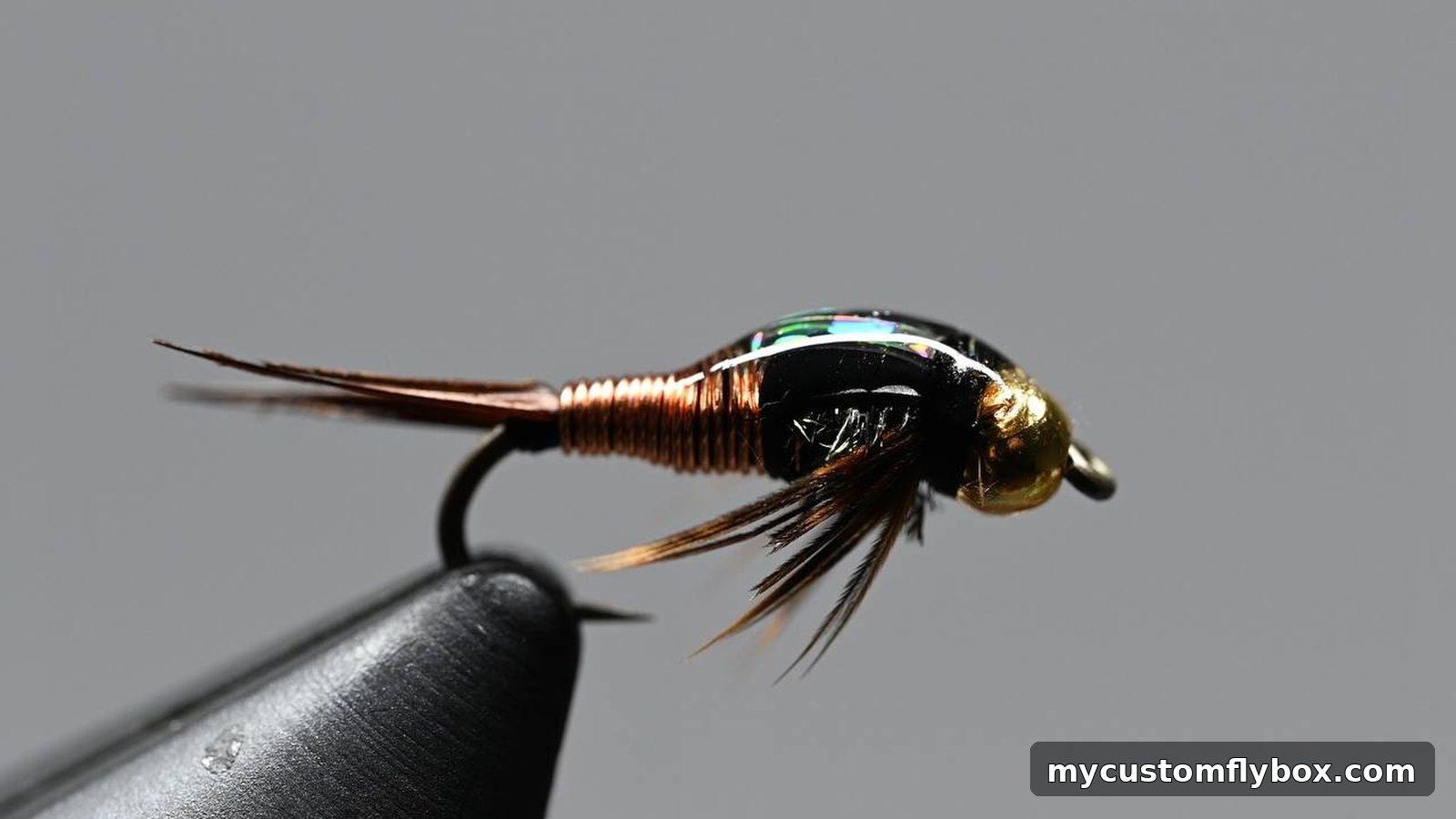 Dark beadhead trout nymph held in a fly-tying vise